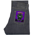 Dark indigo denim jeans folded flat, featuring a vibrant purple and green 'Guardian II' patch on the back pocket.