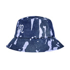 A bucket hat featuring a dark blue denim-like base with a white paint splatter pattern and a white script logo on the side, shown against a plain white background.