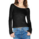 Woman wearing a black long-sleeve top and blue jeans against a white background