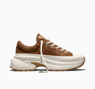 A low-top sneaker in brown suede and textured fabric with a chunky white platform sole, white laces, and a gum outsole, shown from a side profile on a white background.