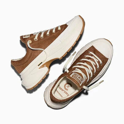 A pair of low-top sneakers shown from angled overhead views on a clean white background. The shoes feature a brown pony hair upper, chunky off-white platform soles, white laces, and a small gold-tone logo detail on the side.