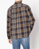 Man wearing a plaid shirt and jeans against a white background