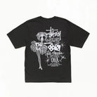 A black short-sleeve t-shirt with a white graphic print on the back, featuring a stylized dancer, dice, and the text 'Stussy ROLLERS' and 'Los Angeles, California USA'.