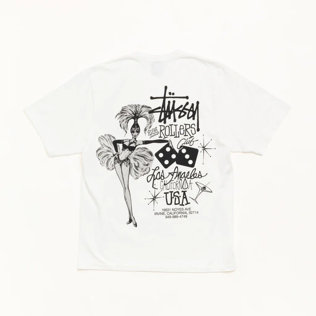 A white Stüssy t-shirt featuring a black graphic print on the back. The graphic includes the Stüssy logo, the words 'Los Angeles, California USA', dice, and a stylized illustration of a woman in a feathered hat.