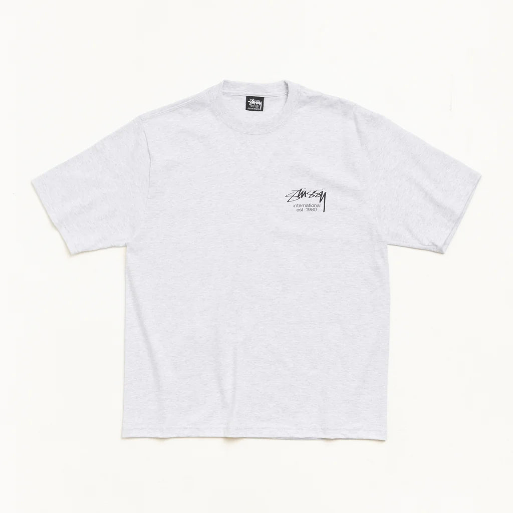 A light gray heather crewneck t-shirt with a small black Stussy logo printed on the left chest, displayed flat against a clean off-white background.