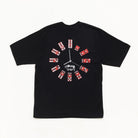 A black short-sleeve t-shirt featuring a graphic design of dominoes arranged in a clock face on the chest, with a white Stussy logo printed below the center graphic.