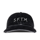 Front view of the Song For The Mute SFTM Cap, a washed black denim baseball cap with “S.F.T.M.” embroidered in off-white across the front.