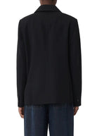 Person wearing a black jacket and dark pants on a white background