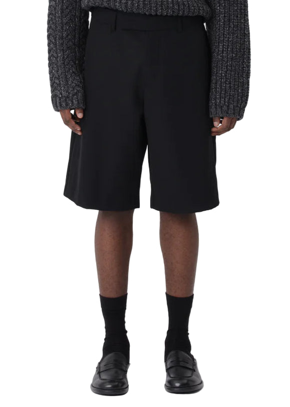 Person wearing a dark patterned sweater and black shorts on a white background