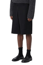 Person wearing a dark textured sweater and black skirt on a white background