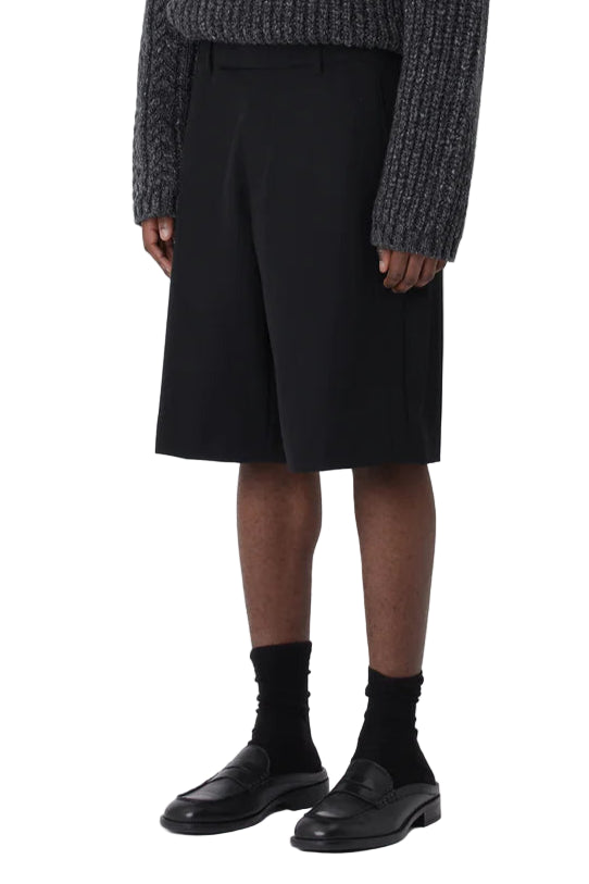 Person wearing a dark textured sweater and black skirt on a white background