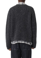 Person wearing a textured sweater and dark pants on a white background