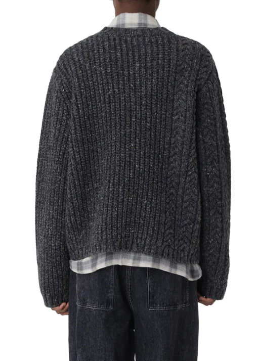 Person wearing a textured sweater and dark pants on a white background