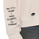 Close up of a cream sweatshirt with graphic print and embroidery details on a white background