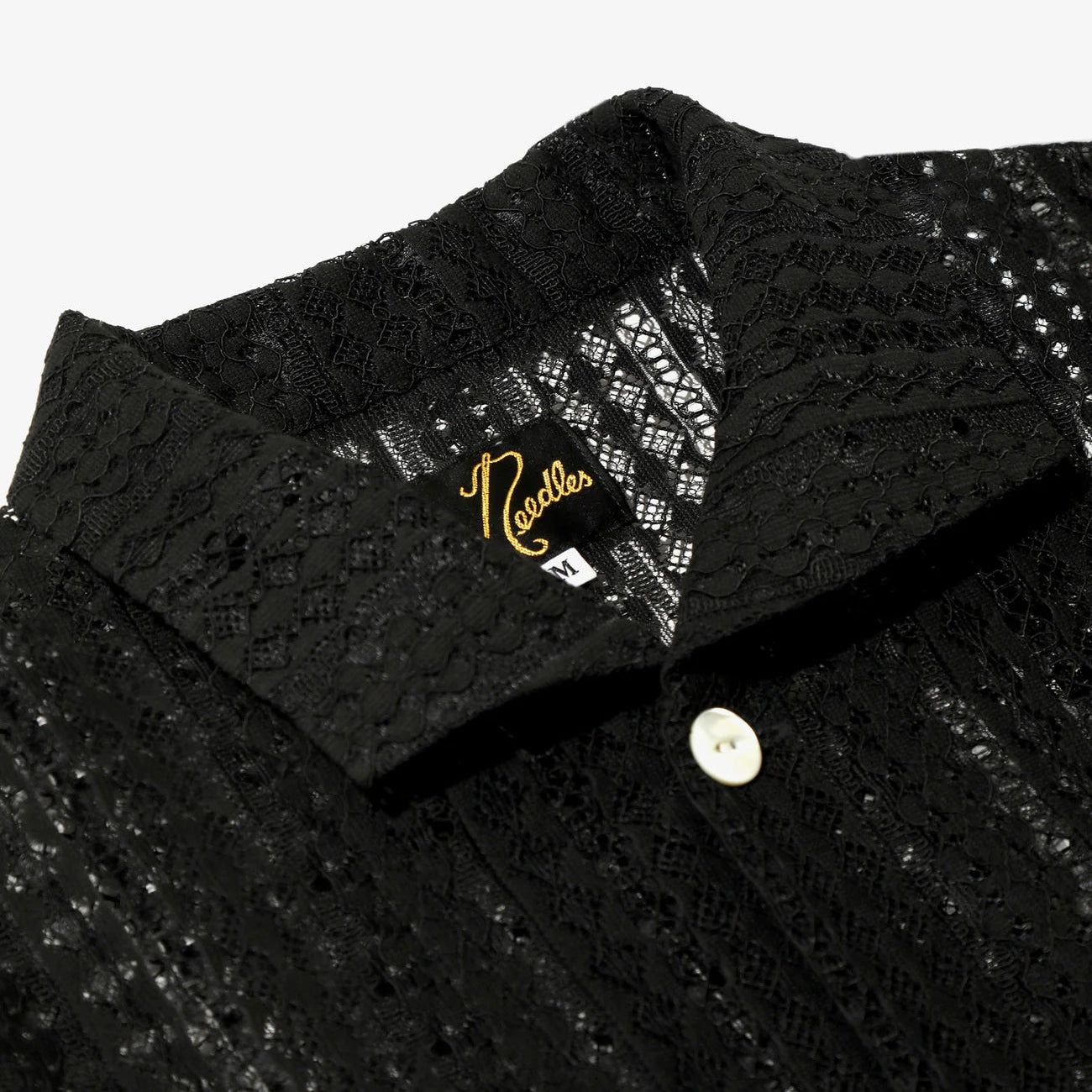 Close-up of a black textured shirt with a brand logo on a white background