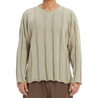 Person wearing a textured beige long-sleeve sweater on a white background