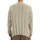 Beige ribbed sweater worn by a person on a white background