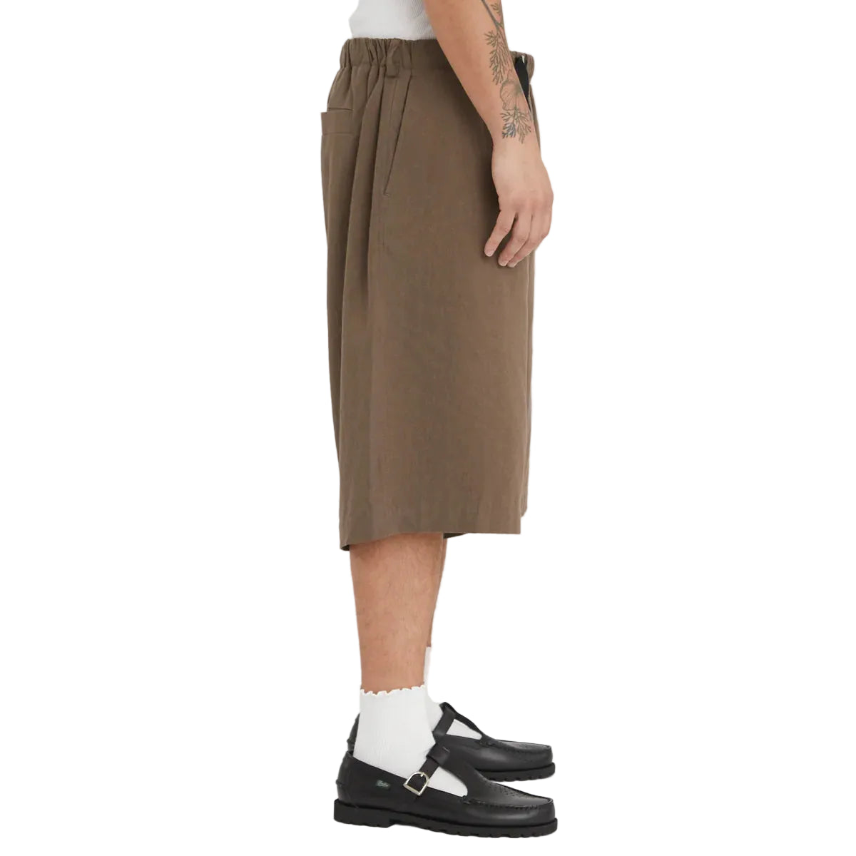 Person wearing a brown shorts with black shoes on a white background