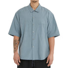 Person wearing a light blue short-sleeve shirt on a white background