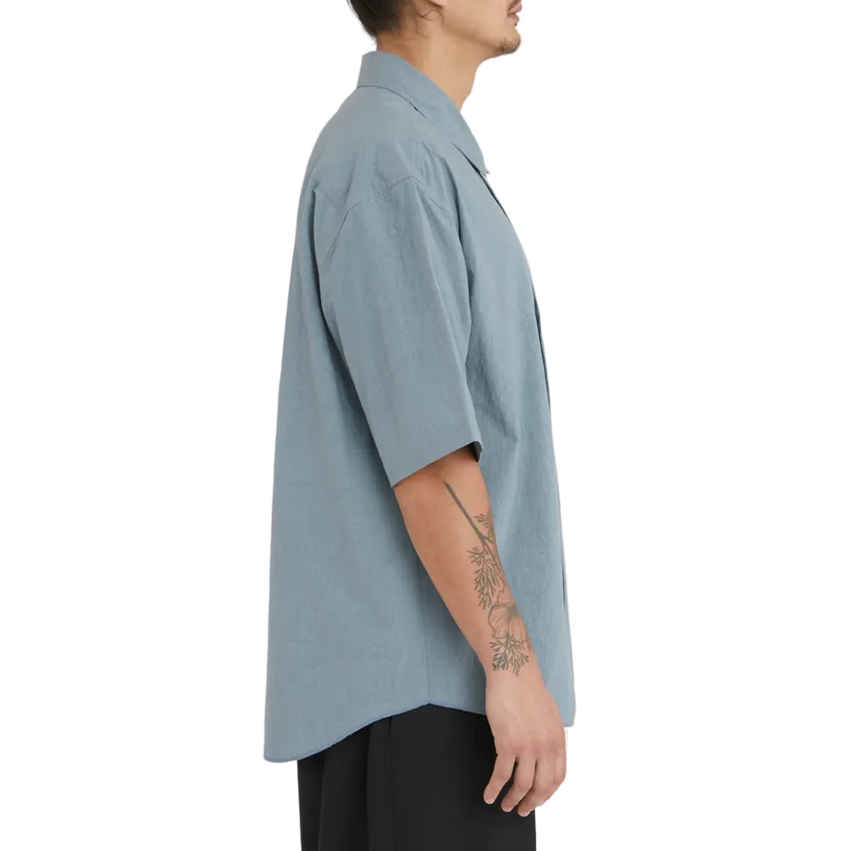 Person wearing a light blue oversized shirt on a white background