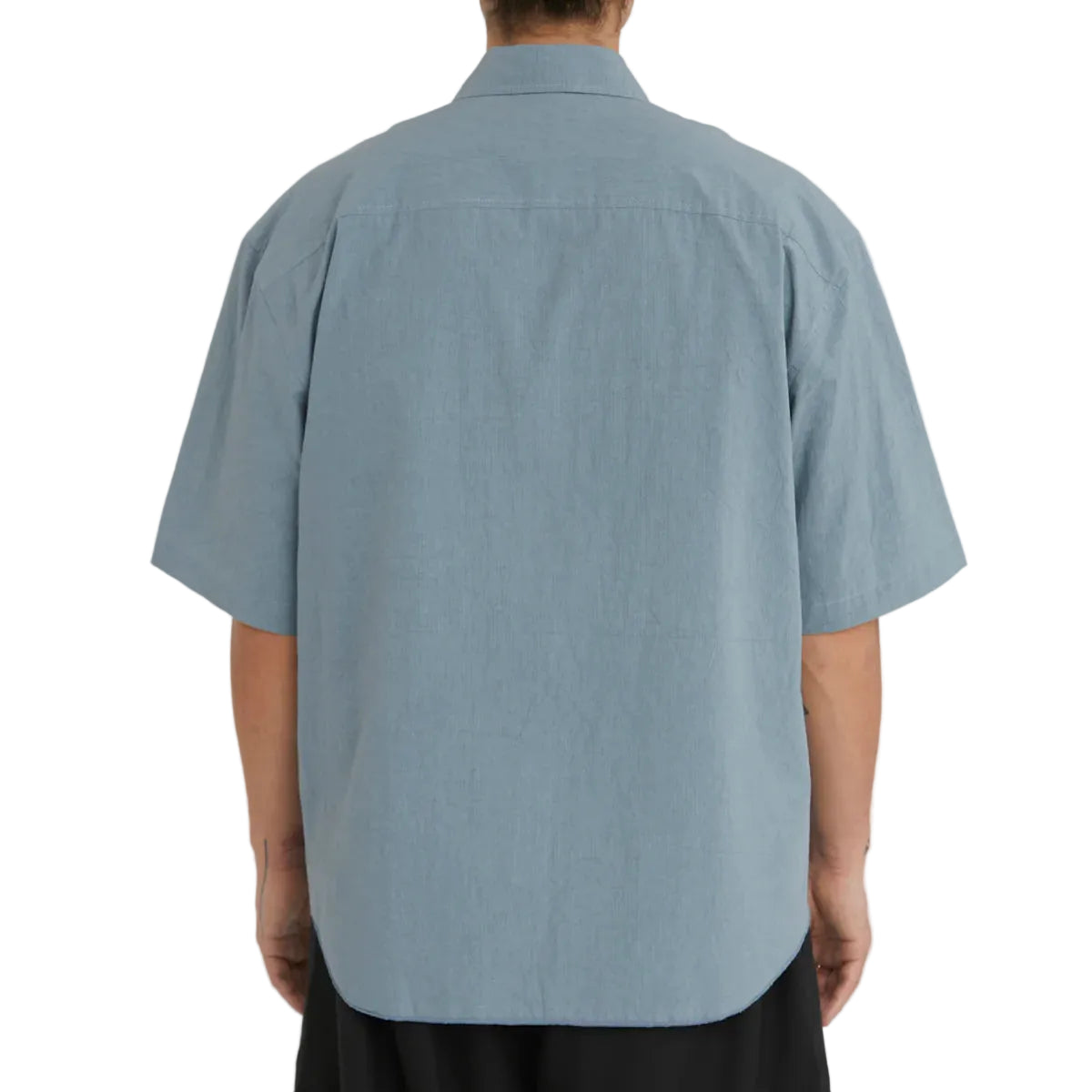 Person wearing a light blue short-sleeve shirt on a plain background