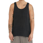 Person wearing a black tank top on a plain background