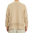 Beige knitted sweater worn by a person on a white background