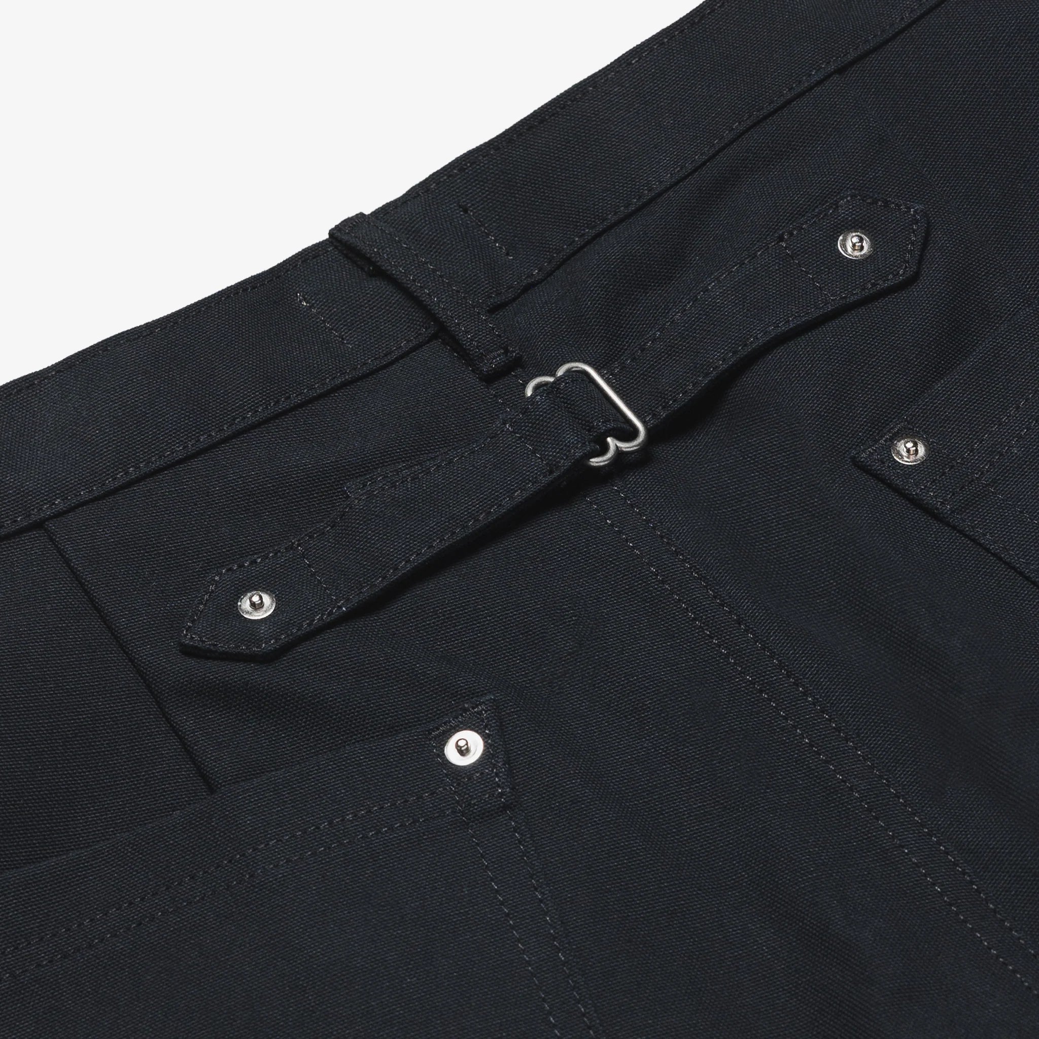 Close-up of a black shorts with a belt and button details on a white background
