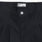 Close-up of black pants with a button and label on a white background