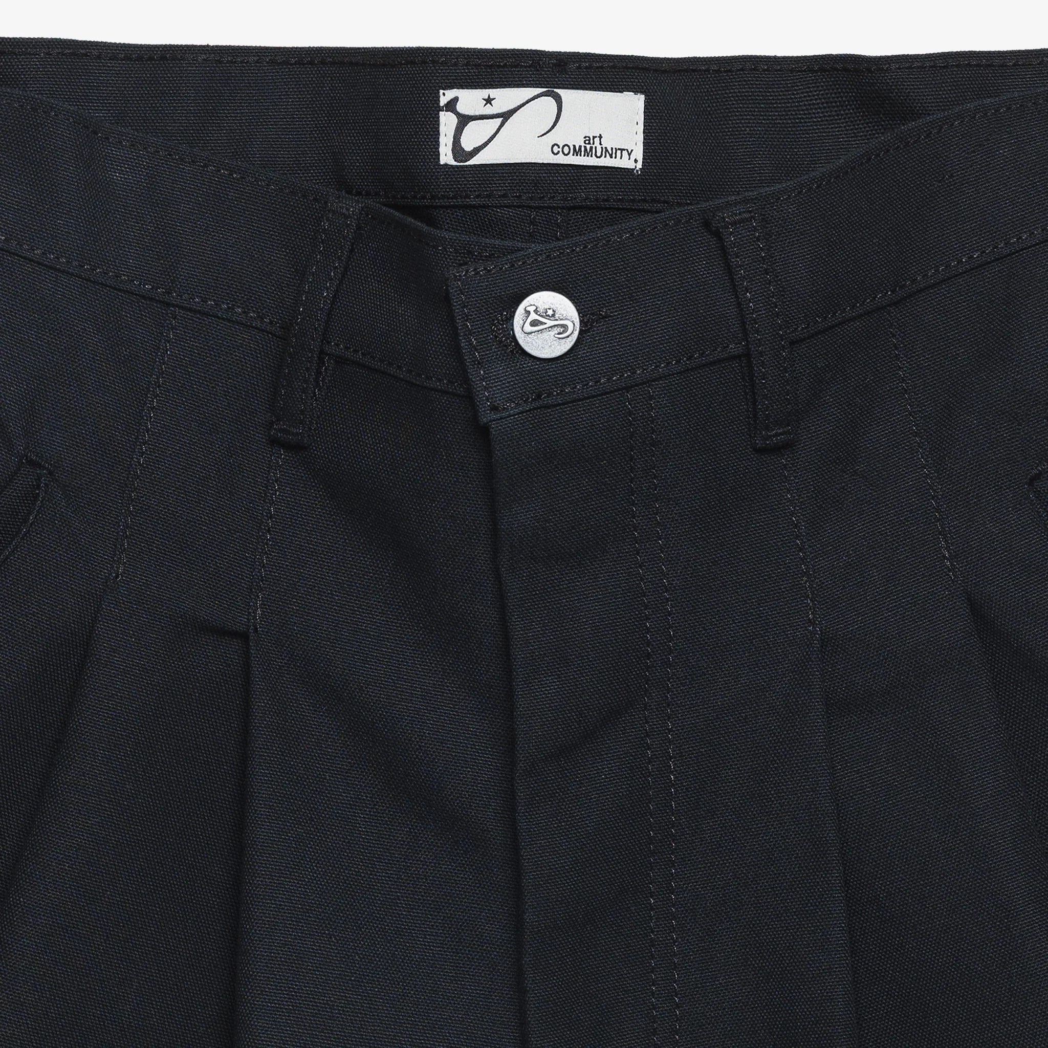 Close-up of black pants with a button and label on a white background