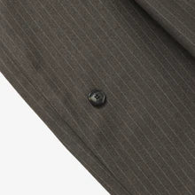 Close-up of a dark gray pinstripe fabric with a button on a white background