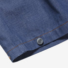 Close-up of a blue denim fabric with a button, on a white background