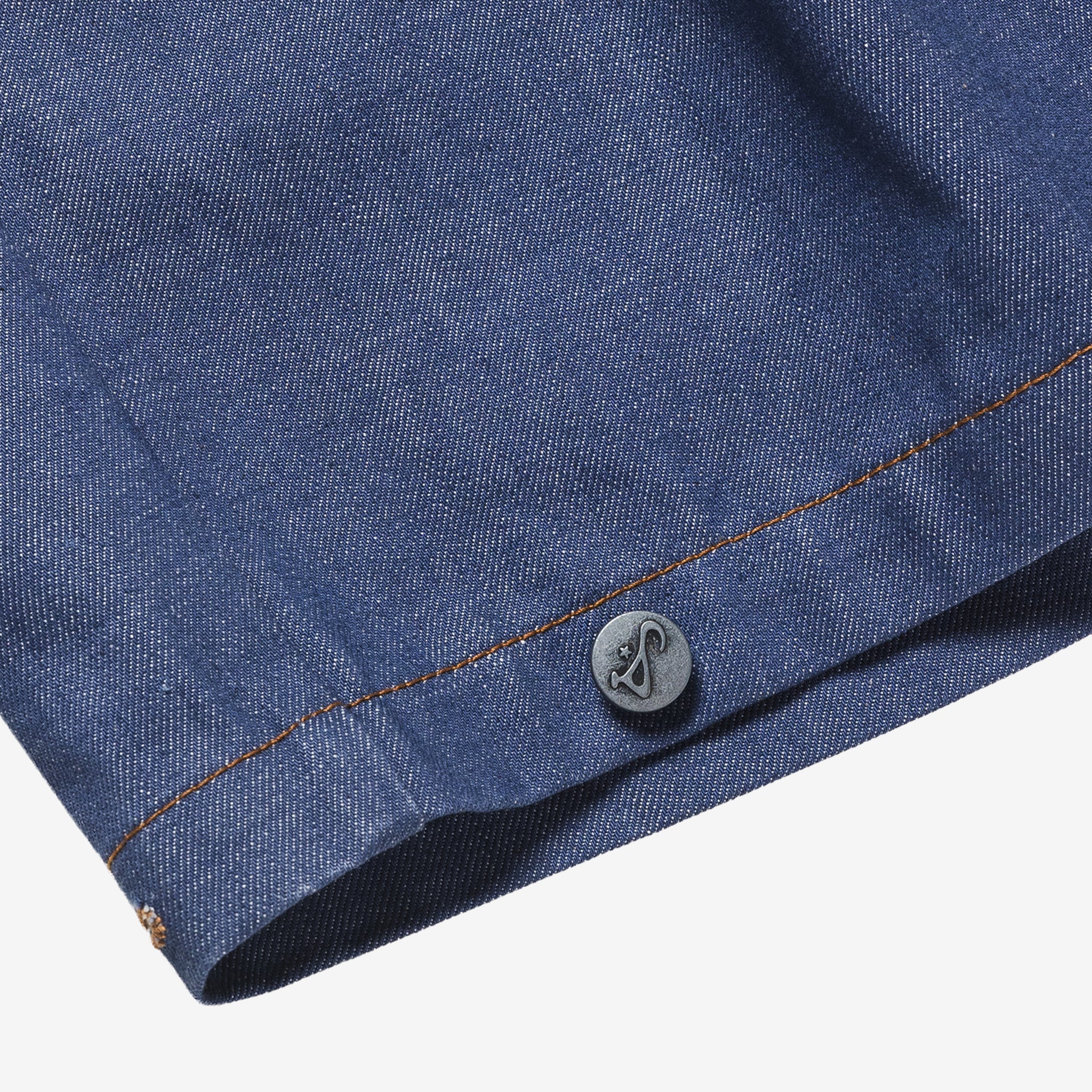 Close-up of a blue denim fabric with a button, on a white background