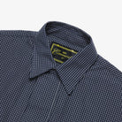 Close-up of a navy checkered shirt with a brand label on a white background