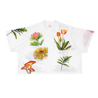 White shirt with colorful floral and mushroom designs on a white background