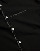 Close-up of a black shirt with white stitching and buttons.