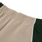 Close-up of beige shorts with green trim on a white background