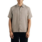 Man wearing a patterned shirt and black pants on a white background