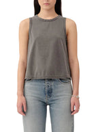 Person wearing a gray sleeveless top and light blue jeans on a white background