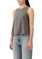 Person wearing a gray sleeveless top and light blue jeans on a white background