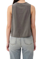 Person wearing a sleeveless gray top and light blue jeans on a white background