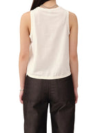 Person wearing a white sleeveless top and dark pants on a white background