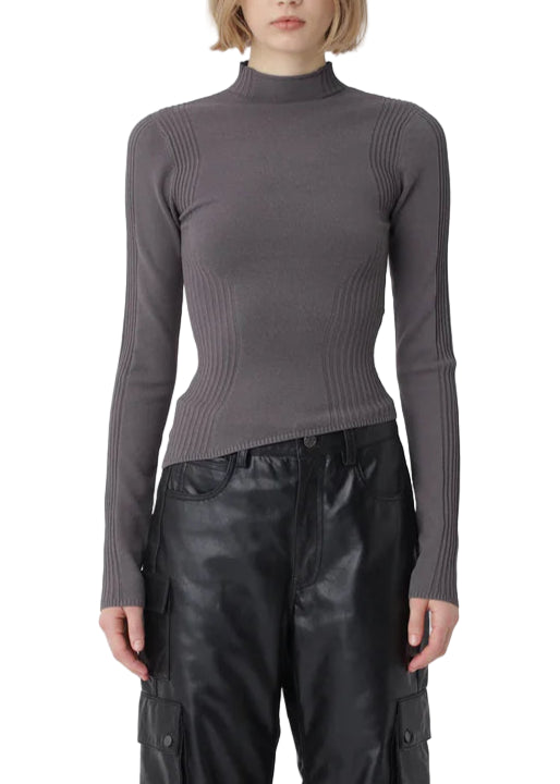 Person wearing a gray turtleneck and black leather pants on a white background