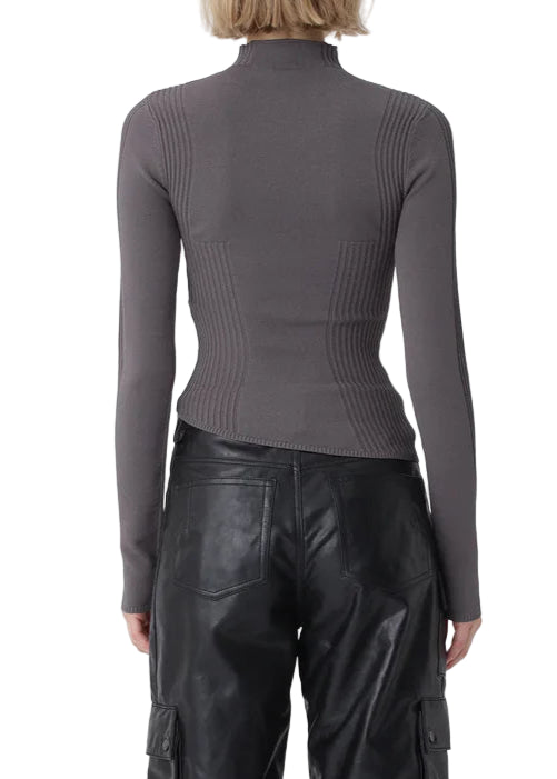 Person wearing a gray long-sleeve top and black leather pants on a white background