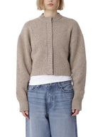 Person wearing a beige sweater and blue jeans on a white background