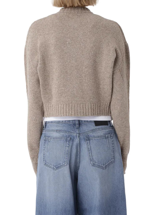 Person wearing a beige sweater and blue jeans on a white background