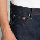 Close-up of dark blue jeans with visible stitching on a plain background