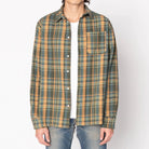 Man wearing a green and brown plaid shirt on a white background