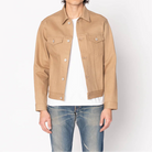 Man wearing a beige jacket over a white shirt and blue jeans on a white background