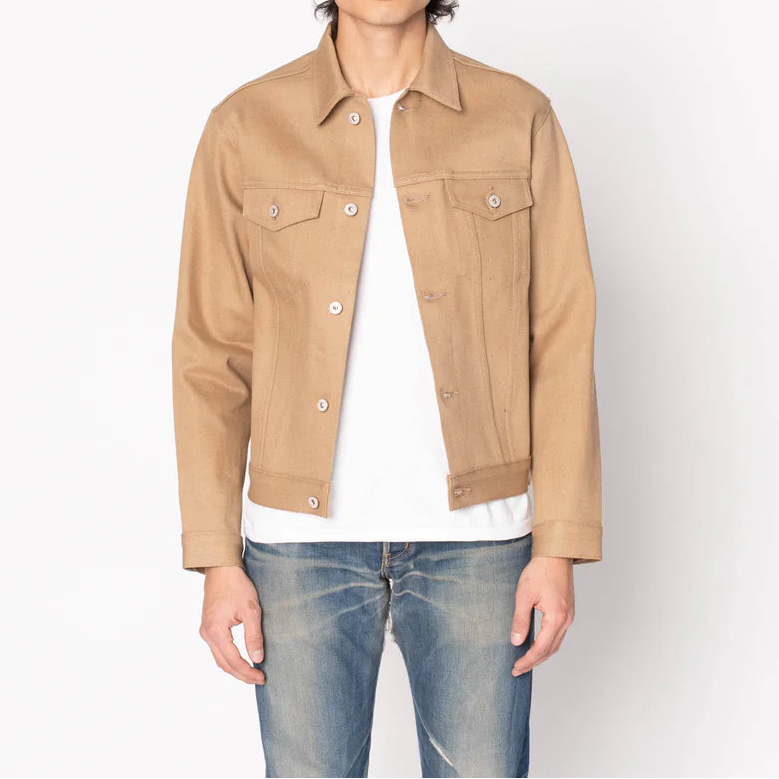 Man wearing a beige jacket over a white shirt and blue jeans on a white background